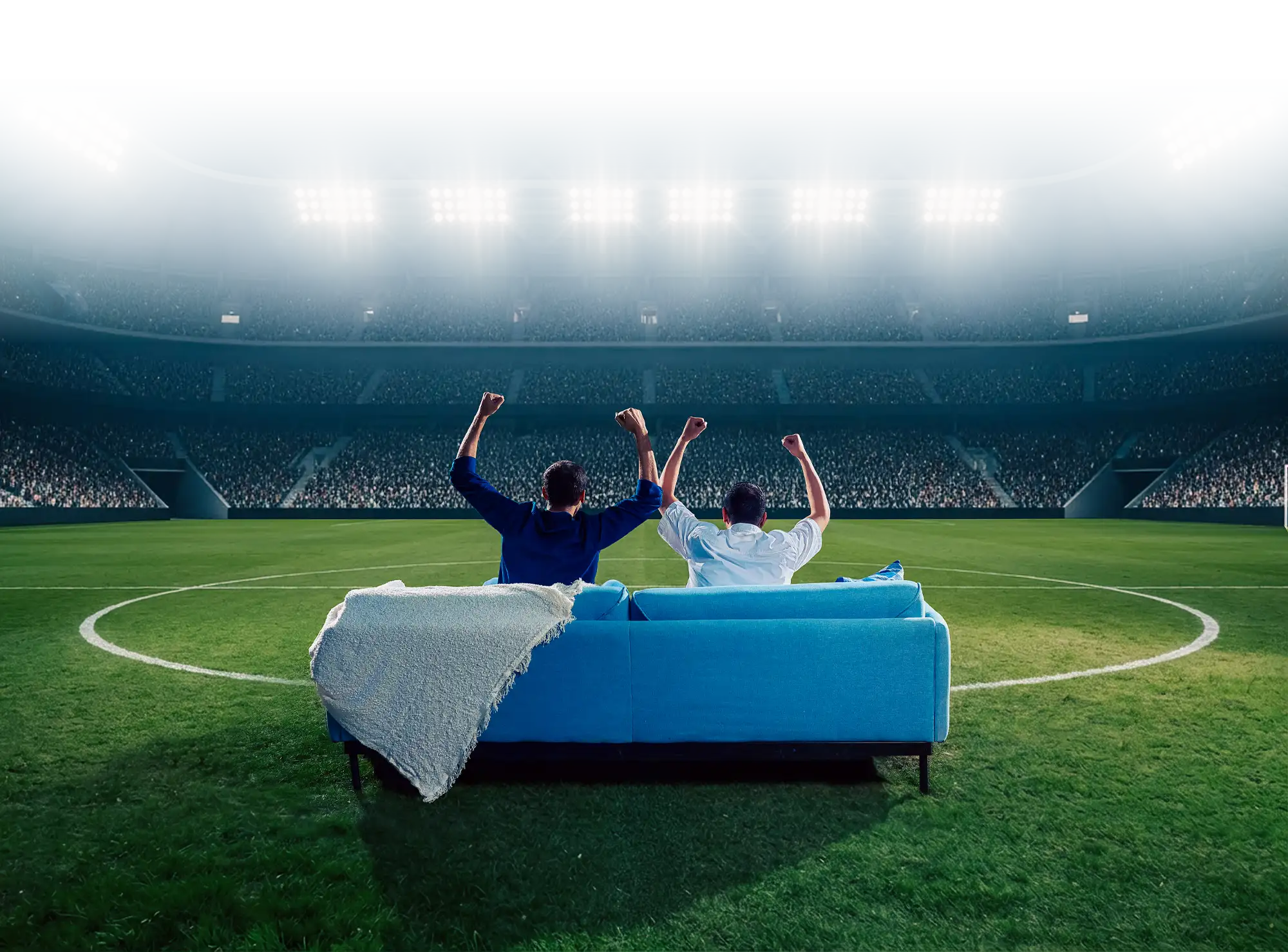Night-time stadium with two people on a blue sofa at center pitch, arms raised toward the crowd; cyan light streaks accent the scene.